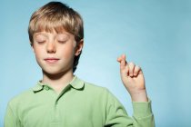 Boy with fingers crossed — Stock Photo