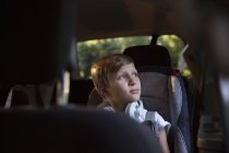 Boy in car back seat gazing out through window — Stock Photo