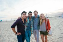 Група друзів, що стоять разом на пляжі, сміється — стокове фото
