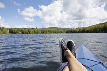 Feet on canoe with view of lake and green forest — Stock Photo