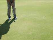 Человек играет в гольф на зеленом поле — стоковое фото