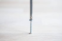 Close up of Screwdriver and screw in wooden surface — Stock Photo