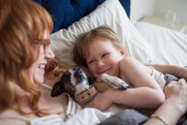 Mutter, Tochter und Hund liegen im Bett — Stockfoto