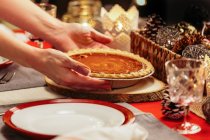 Woman placing pie on festive table — Stock Photo