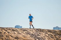 Baixo ângulo de visão do homem adulto médio correndo em duna de areia, Dubai, Emirados Árabes Unidos — Fotografia de Stock