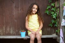Porträt eines Mädchens auf Bank mit einem Eimer frischer Erdbeeren — Stockfoto
