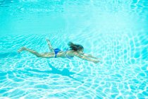 Mujer en bikini nadando en la piscina bajo el agua - foto de stock