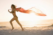 Donna che corre con il pareo sulla spiaggia — Foto stock