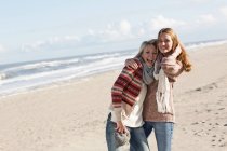 Lächelnde Frauen, die sich am Strand umarmen — Stockfoto