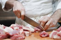 Açougueiro cortando carne em pedaços — Fotografia de Stock