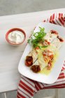 Plate of burritos with sour cream — Stock Photo