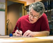 Older man writing at desk — Stock Photo