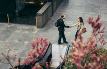 Vista de ángulo alto del hombre de negocios y la mujer estrechando la mano en la ciudad - foto de stock