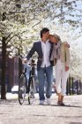 Couple walking bicycle in park — Stock Photo