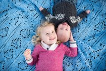 Overhead portrait of girl on blue picnic blanket with baby brother — Stock Photo