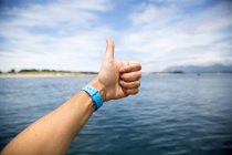 Female hand giving thumbs up over Nehalem Bay, Oregon, USA — Stock Photo