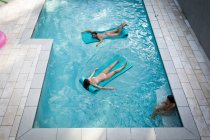 Високий кут огляду двох жінок, які купаються на надувних барвах у басейні (Санта - Роза - Біч, Флорида, США). — стокове фото