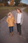 Zwei junge Mädchen gehen Hand in Hand die Landstraße entlang — Stockfoto
