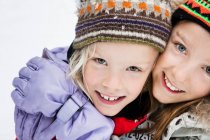 Улыбающиеся девушки, обнимающиеся в снегу — стоковое фото