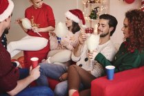 Giovani donne e uomini che mangiano candyfloss sul divano alla festa di Natale — Foto stock
