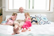 Portrait d'homme mûr entre deux filles au lit — Photo de stock
