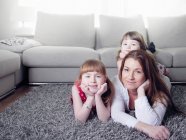 Mother and daughters laying on rug — Stock Photo