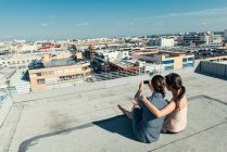 Businesswomen taking selfie with smartphone on roof terrace, Los Angeles, California, Estados Unidos - foto de stock