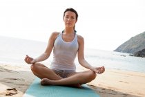 Mulher praticando ioga em uma praia — Fotografia de Stock