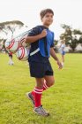Niño llevando pelotas de fútbol en el campo - foto de stock