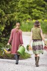 Vista trasera de dos mujeres que llevan verduras - foto de stock