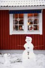 Сніговики стоять біля будинку, хлопчик на задньому плані — стокове фото