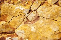 Gros plan de la surface rocheuse fissurée jaune — Photo de stock