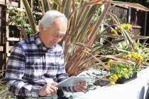 Пожилой человек с помощью планшетного компьютера на открытом воздухе — стоковое фото