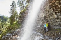 Jeune couple debout sous la cascade, regardant dehors, Tyrol, Autriche — Photo de stock