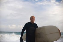 Серфер с доской на пляже — стоковое фото