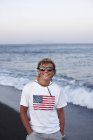 Улыбающийся мальчик стоит на пляже — стоковое фото
