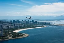Airplane flying over coastline — Stock Photo