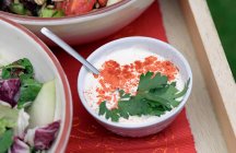 Свежие салаты и соус в мисках — стоковое фото