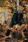 Mature man splitting logs in autumn forest, Upstate New York, USA — Stock Photo