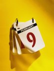 Flip calendar hanging on vivid yellow wall — Stock Photo