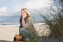 Жінка сидить на пляжі — стокове фото