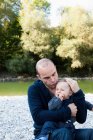 Father holding crying baby by creek — Stock Photo