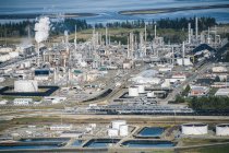 Lagertanks und Rauchschwaden in Ölraffinerie an der Küste — Stockfoto