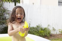 Дівчина в надувному басейні, схвильована іграшкою — стокове фото