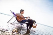 Человек с собакой в шезлонге в ручье — стоковое фото