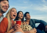 Group of friends sitting together outdoors, laughing — Stock Photo