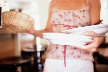 Kellnerin trägt Weidenkorb und Geschirr, beschnitten — Stockfoto