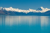 Snowy mountains and rural lake — Stock Photo