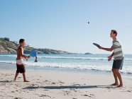 Отец и сын играют в футбол на пляже — стоковое фото