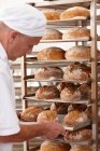 Chef poniendo bandeja de pan en rack - foto de stock